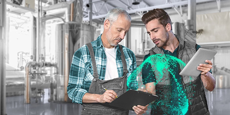 Two workers reviewing a tablet in a manufacturing setting