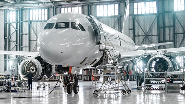 Ein Düsenflugzeug in einem Hangar mit für die Wartung geöffneten Triebwerken.
