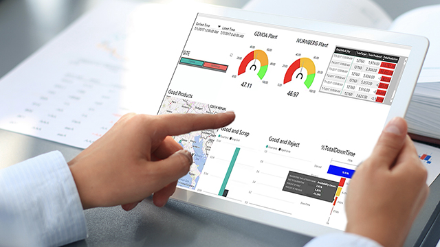 A person holds a tablet displaying graphs and charts, and points at them with their other hand
