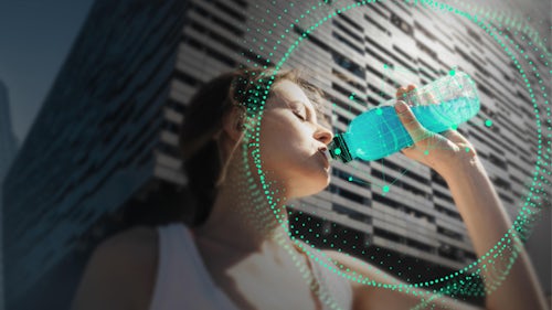 Eine Frau trinkt nach dem Laufen einen blauen Energy-Drink aus einer Flasche
