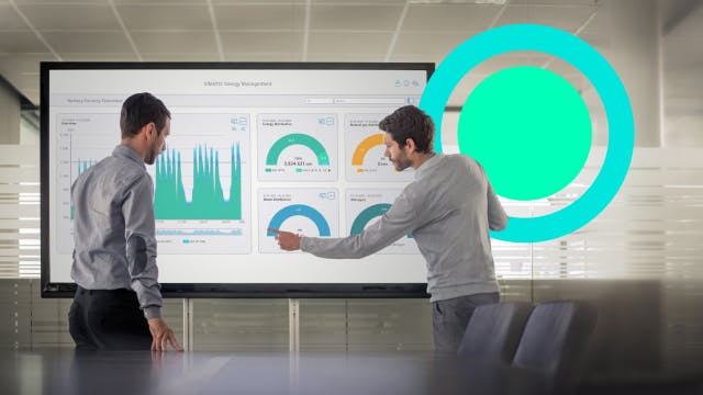 Two coworkers explaining a graph to a colleague in a conference room.