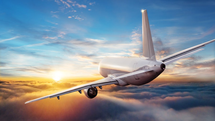 A plane taking off from the runway against a deep blue sky as night falls