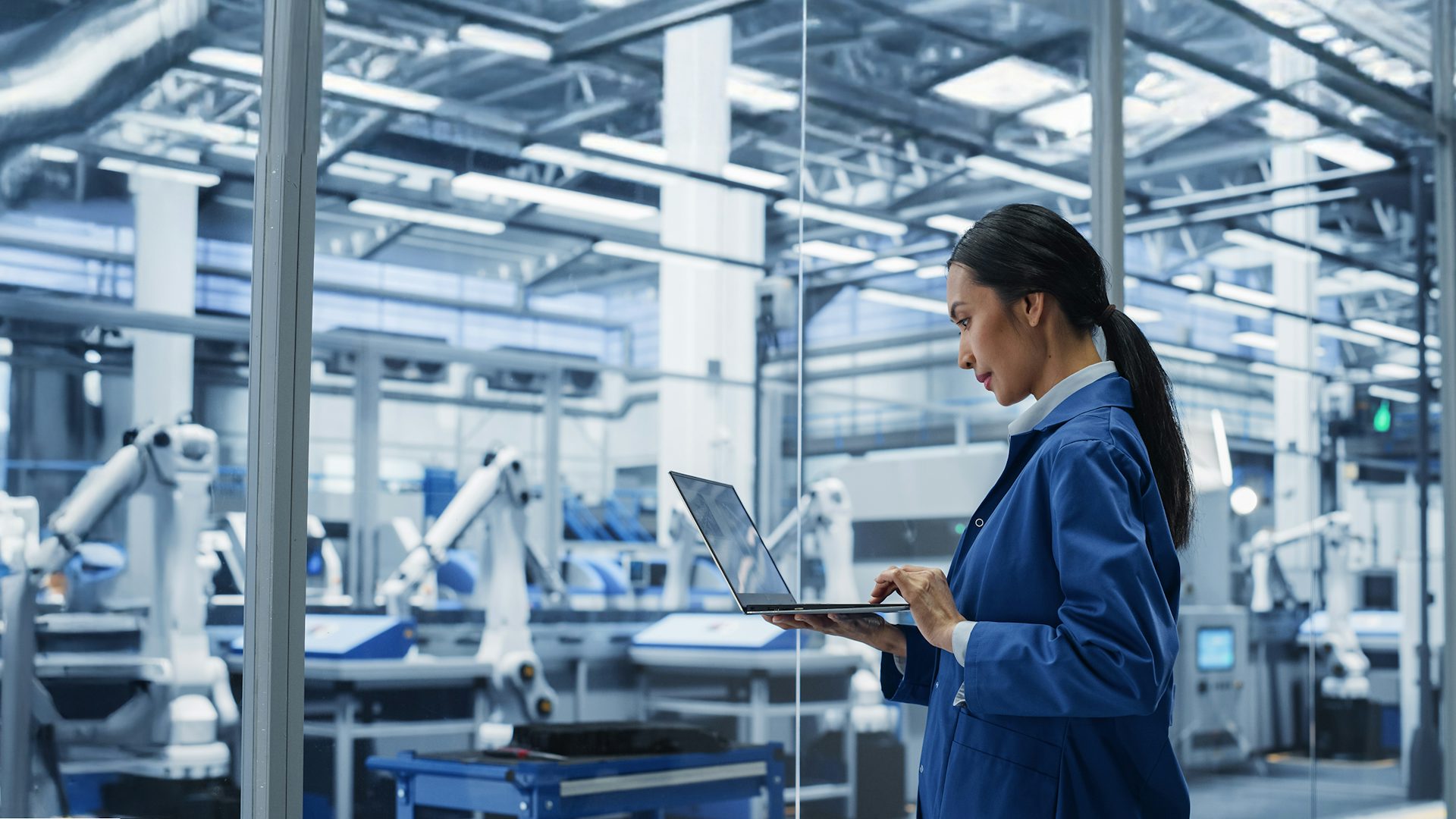 Female engineer using laptop at a factory facility.