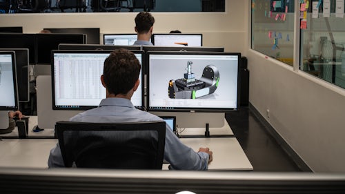 Dva inženýři pracují v kanceláři na návrzích v softwaru CAD.