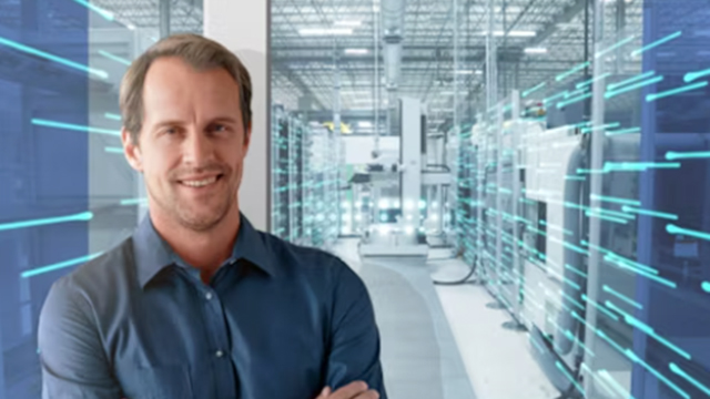A man in the foreground with a manufacturing plant behind him