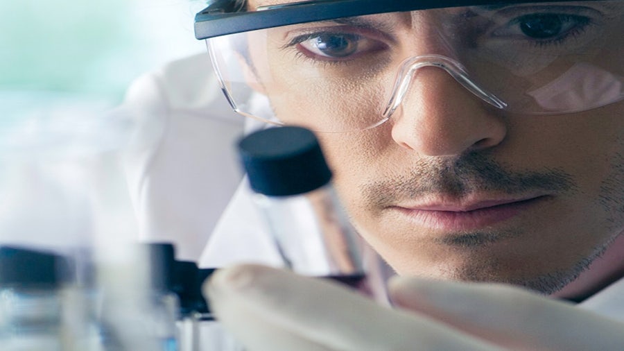 Scientist in safety glasses examining a sample.