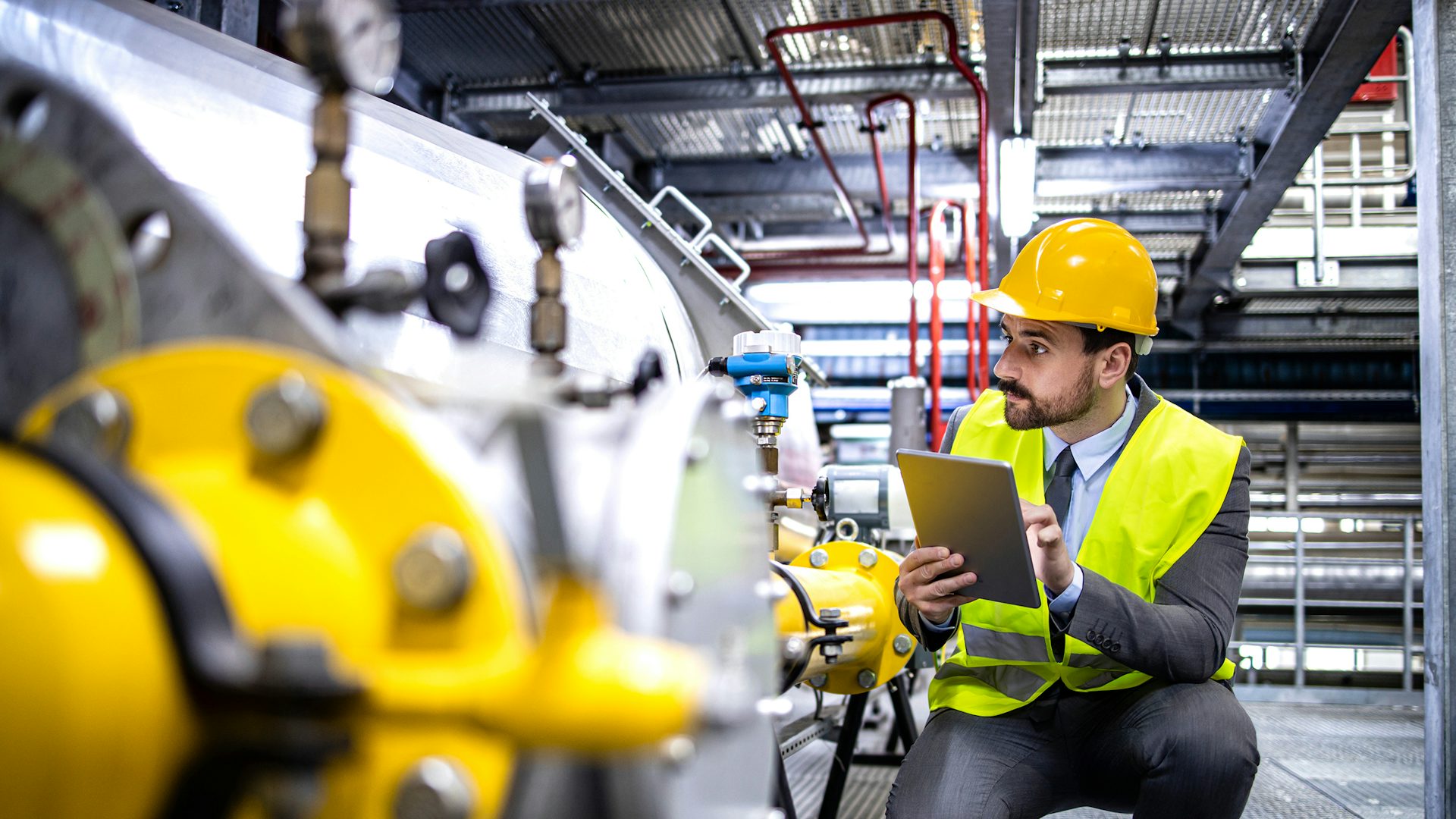 A man leaning down and checking the quality of a tool in a factory.