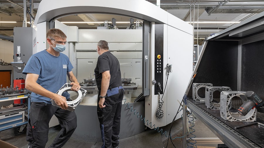 Two workers making parts on a CNC