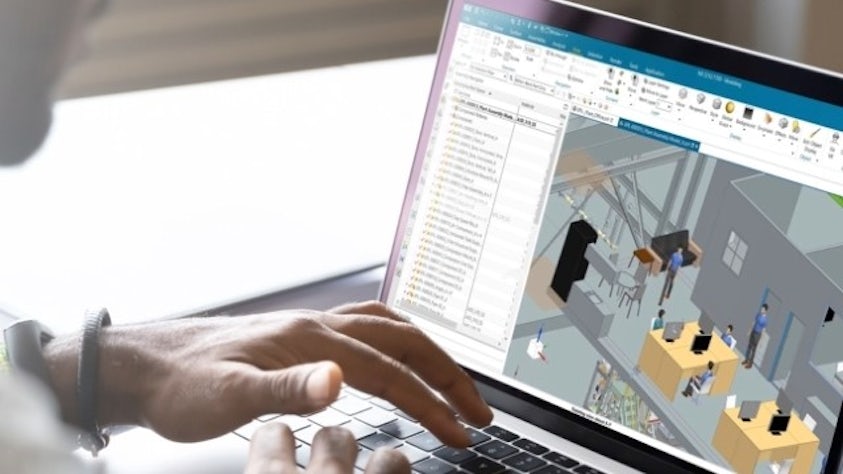 A laptop with NX CAD software with a design of a factory with an office, including people from NX Human.