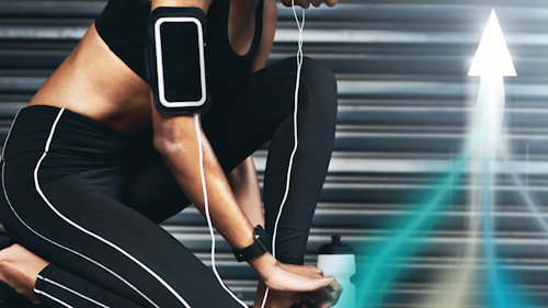 Frau in Sportkleidung schnürt ihre Laufschuhe, bevor sie losläuft. Sie hat ein Mobiltelefon mit Kopfhörern, eine Smartwatch und eine Flasche Wasser bei sich.