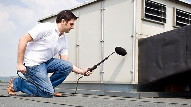 An engineer holding a mic performing intensity-based sound power testing while ensuring compliance with ISO measurement standards for both scanning and point-by-point methods.