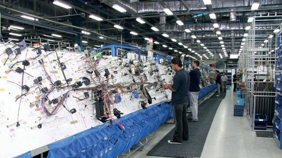 EE engineers working on a wire harness foamboard in a wire harness production facility.