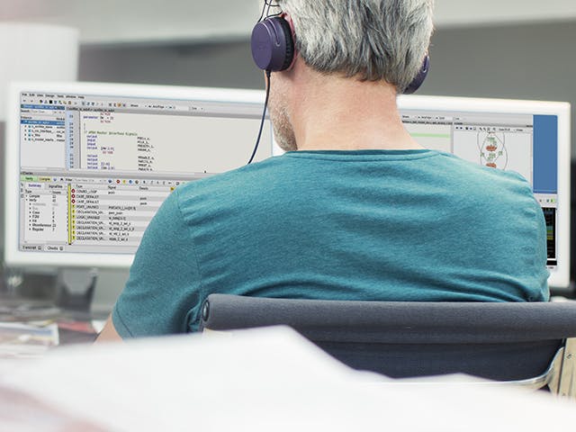 Engineer is using Questa Inspect tool on his desktop while wearing a headset.