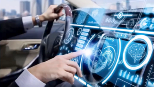 A hand on the steering wheel of a car, with digital graphics laid over the dashboard