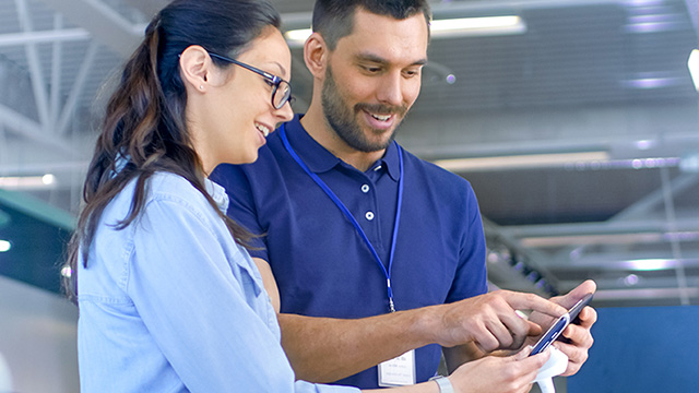 Two workers looking at a tablet inside a factory.