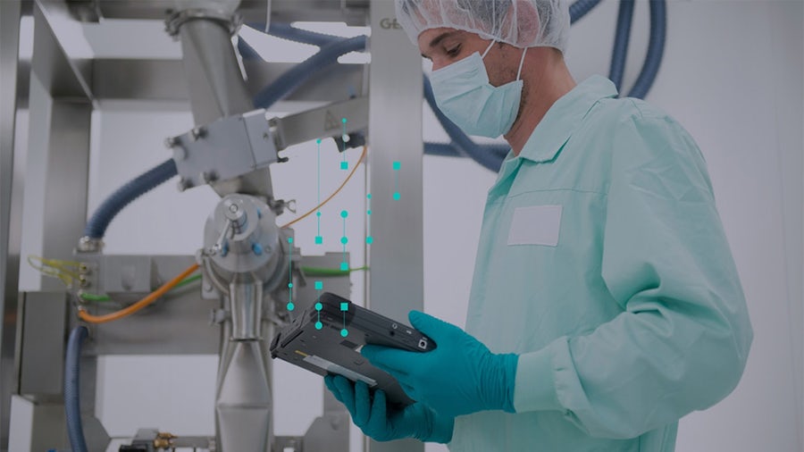 Operator in a sterile manufacturing environment monitoring continuous production machinery via tablet.