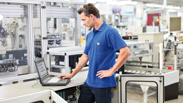Man in a shop working on a laptop.