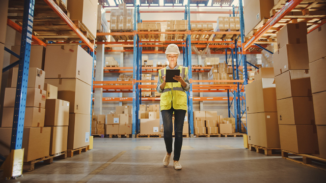 Person walking through storage facility with tablet.