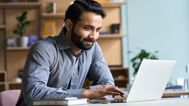 An engineer is working on his laptop and smiling