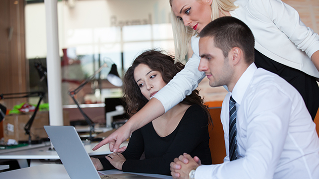 Tři osoby v kanceláři při práci s notebookem