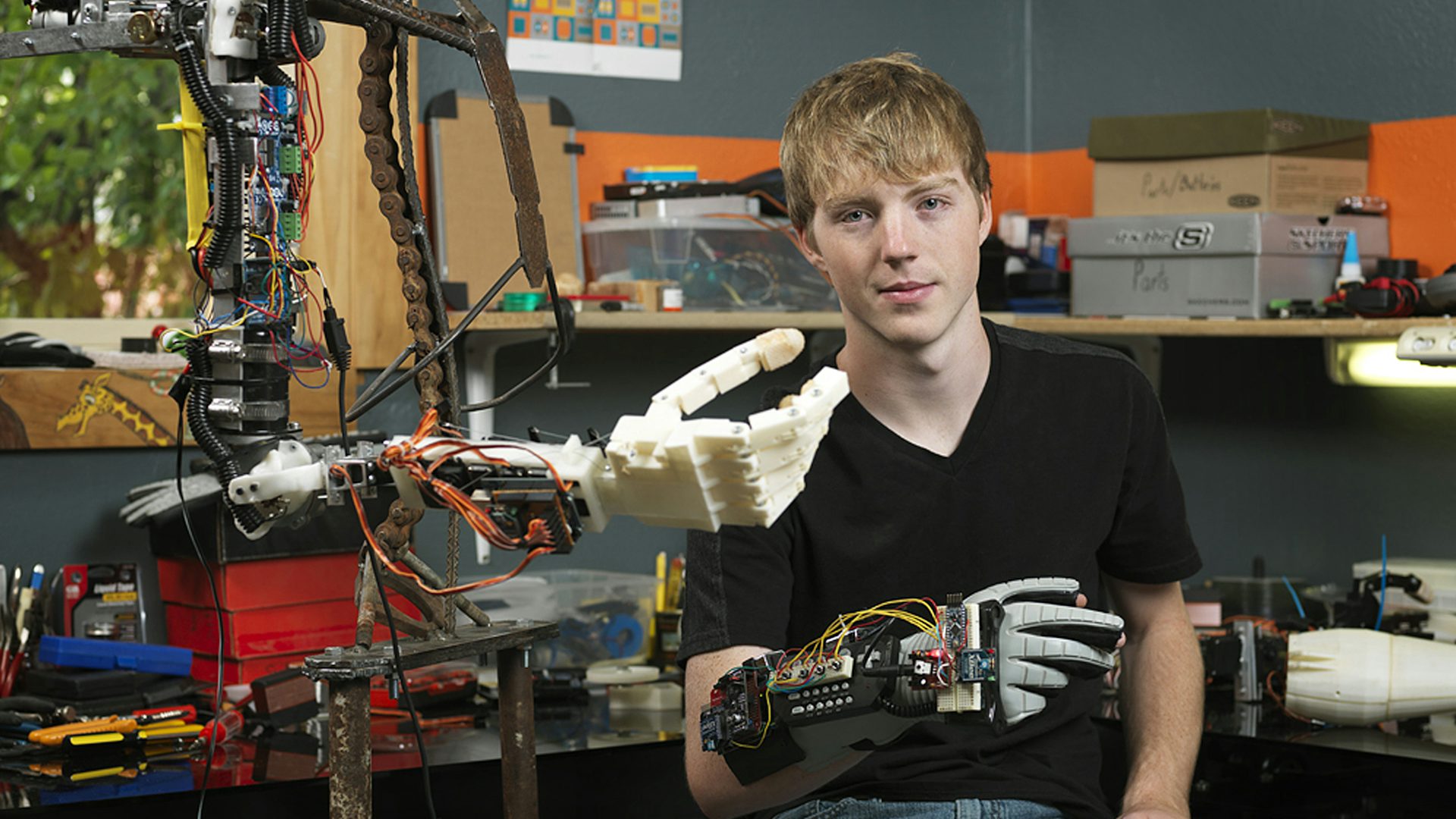 Designer wearing a telemetry glove, next to a prototype arm and hand