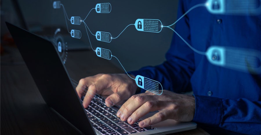 A close up shot of a man typing on a laptop with an overlay of blue security keys in a futuristic sense.