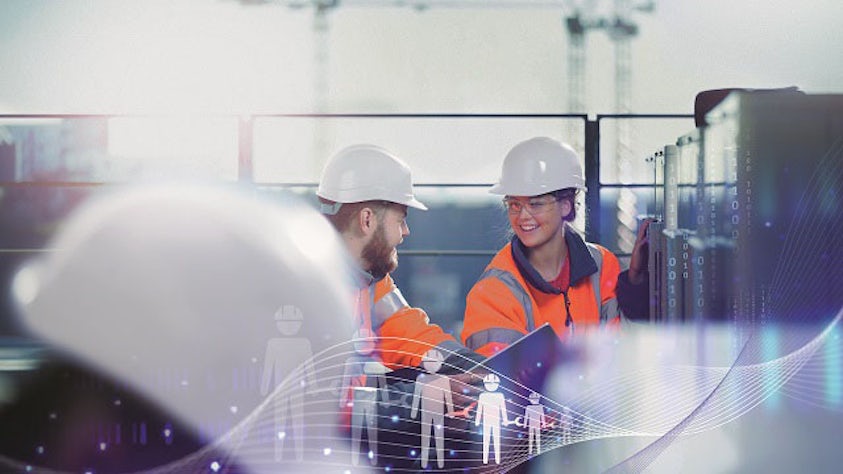 Two workers wearing hardhats in a factory