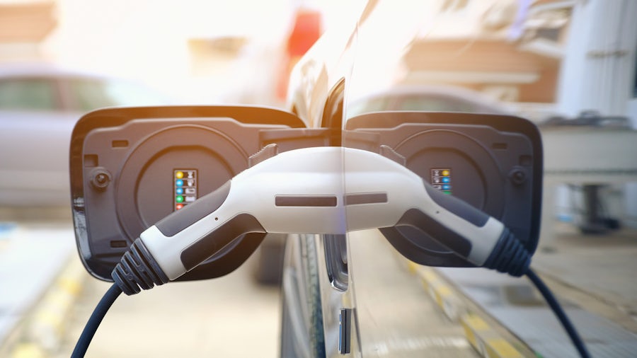 EV充電ステーションのコードで電気自動車を充電する人