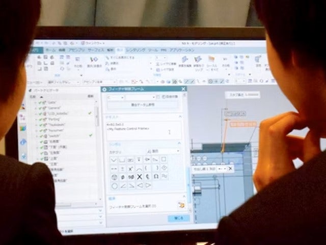 Two Chuo University students on a desktop computer with an assembly open in NX CAD software.