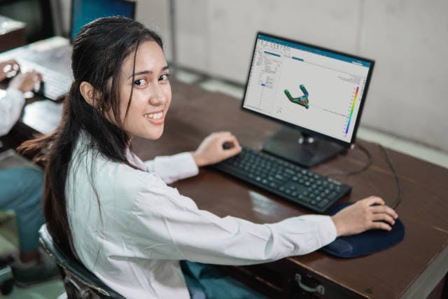 A female student sitting at a computer screen with keyboard, mouse and 3d modeling software on the screen.