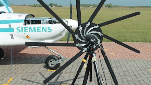 A sound camera in front of a propellor plane with the Siemens logo performs acoustics testing for aircraft noise reduction