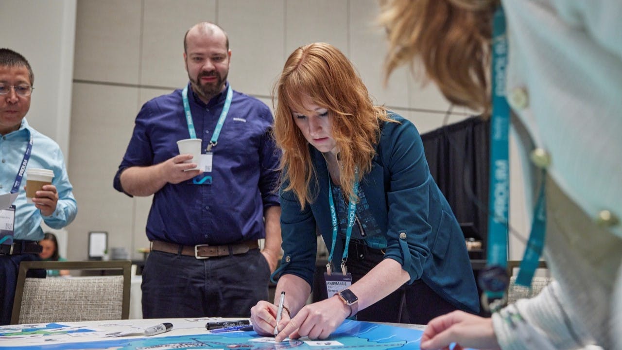 Woman writing something on a card at an interactive session at Realize LIVE Americas.