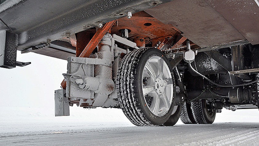 A trailer tire on a snowy pavement