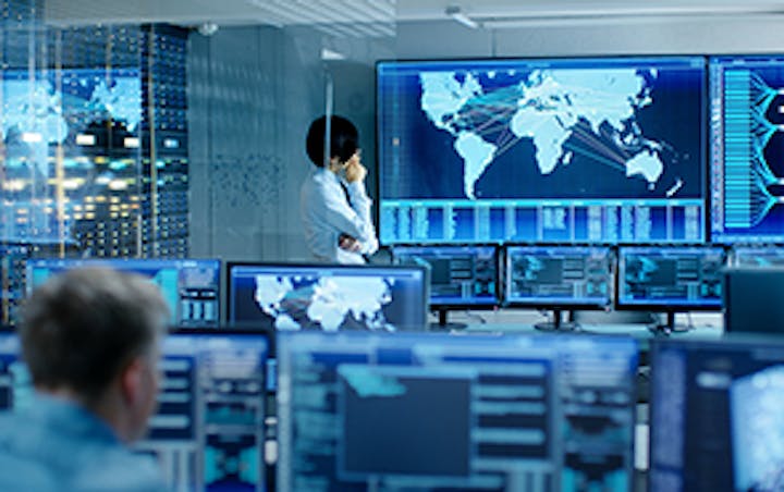 Ein Mann blickt in einem Raum mit zahlreichen Bildschirmen auf einen wandmontierten Monitor, der eine Weltkarte zeigt