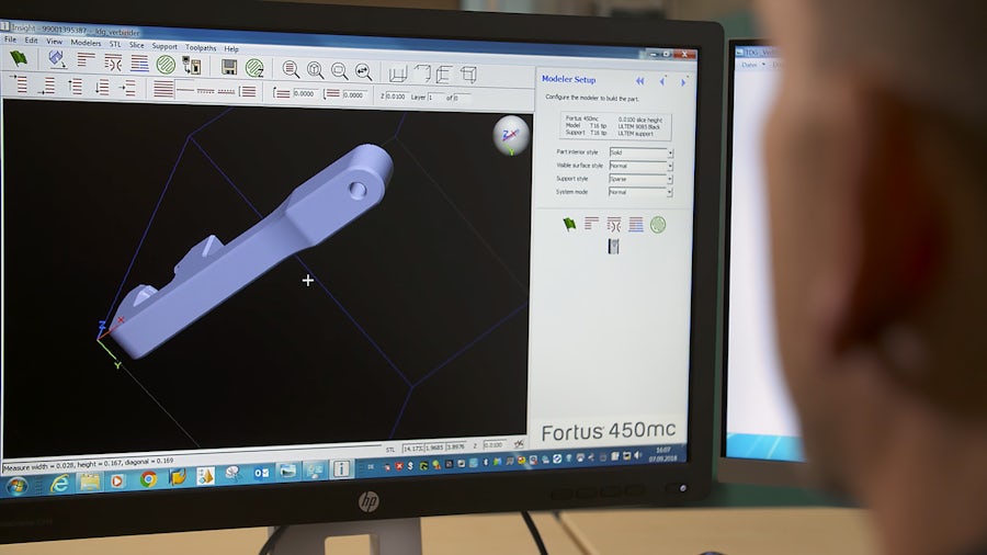 A man looking at a computer-generated 3D model of a part for manufacturing. 
