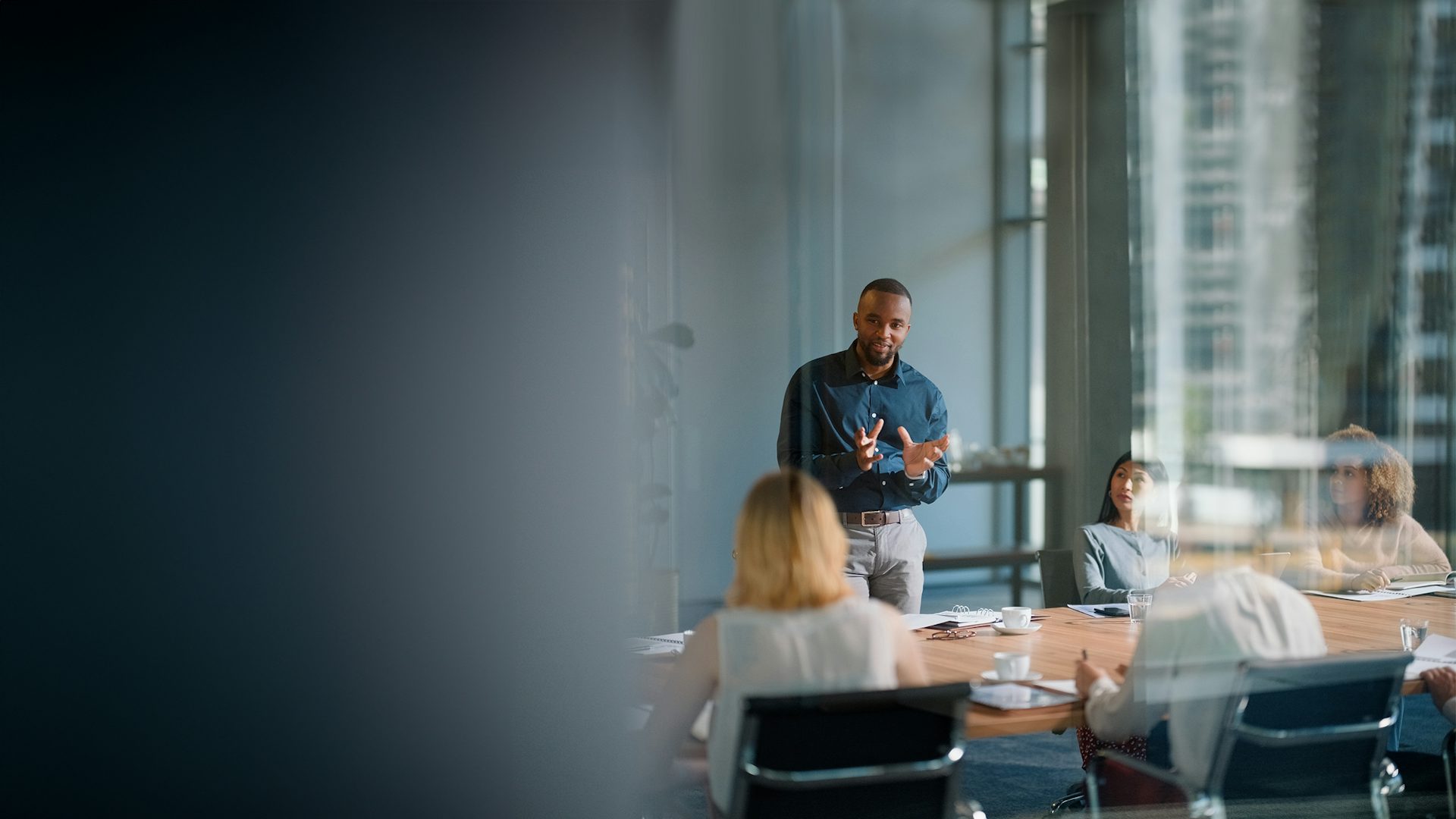 Businessman standing in a meeting and having a discussion with colleagues in an office.