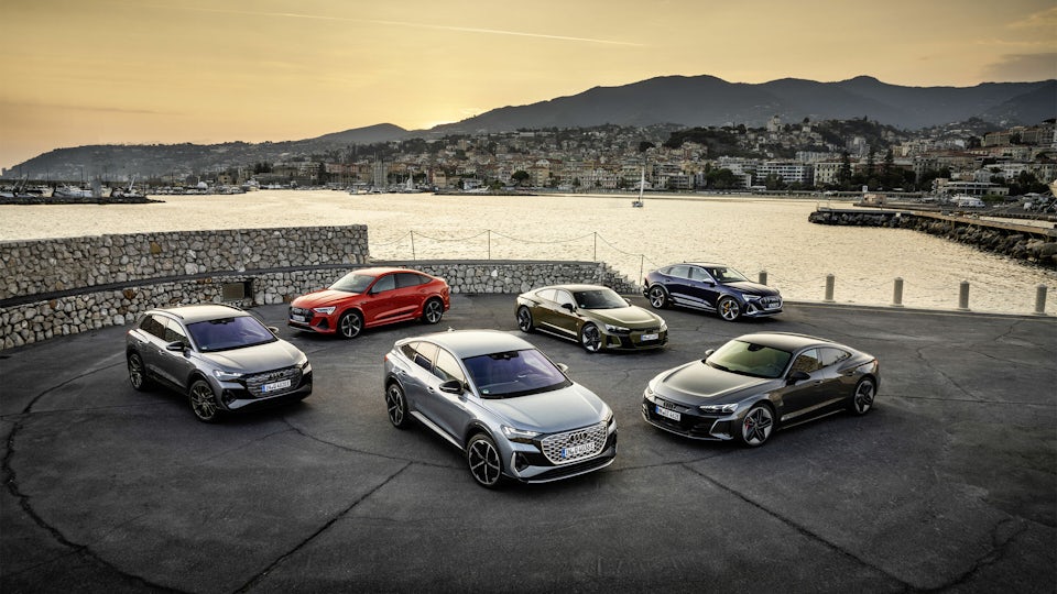 Six Audi automobiles parked next to a body of water