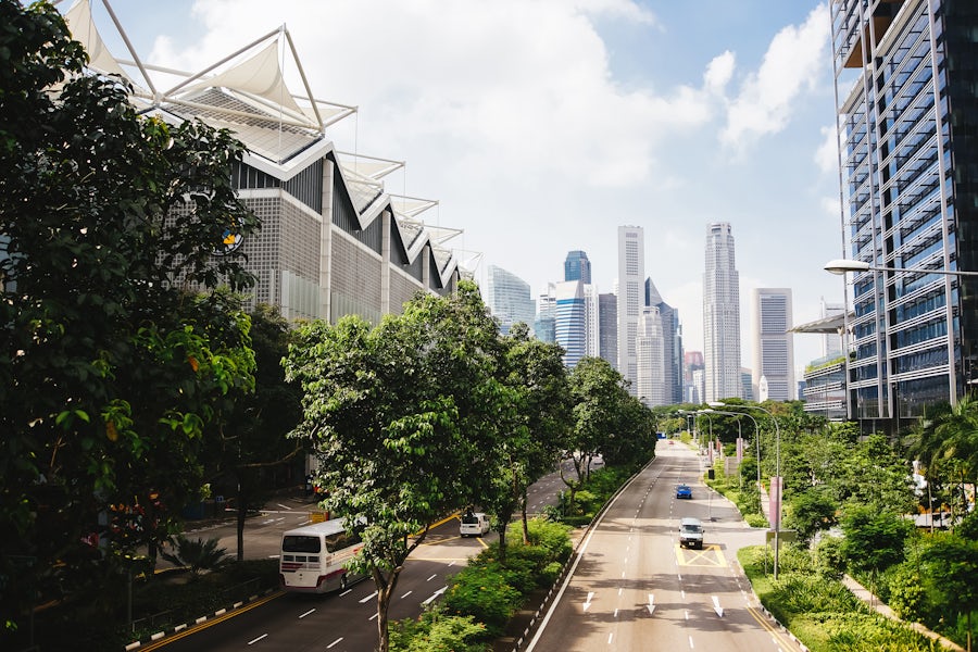 Six-lane road that leads through a modern city with many green spaces.