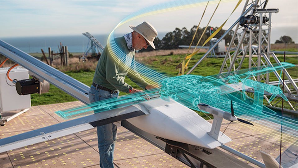 Man in a field working on a drone, which is overlayed with a digital twin.