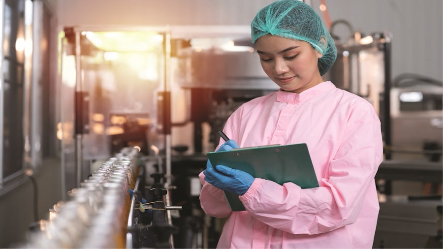 Factory worker conducting quality checks on a production line in consumer packaged goods manufacturing