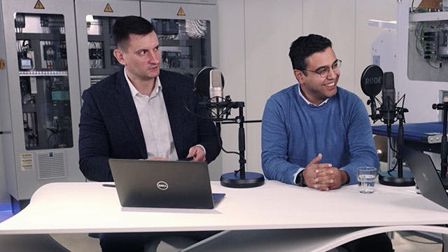 Zwei Personen an einem Schreibtisch nehmen einen Podcast auf