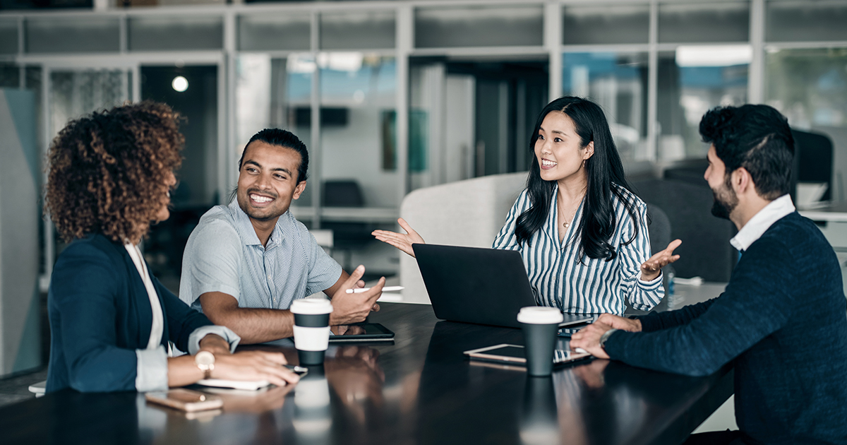 Teammitglieder im Büro bei der Zusammenarbeit mit Laptop, Tablets und Mobiltelefon