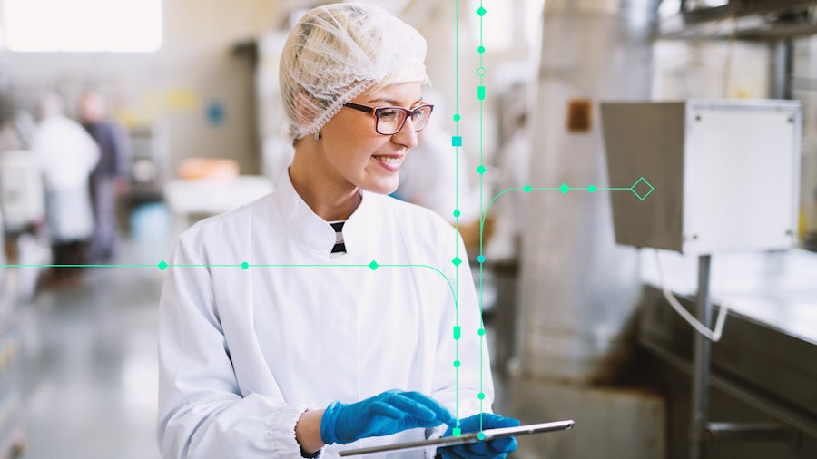 A woman in a medical device manufacturing plant holding a tablet while looking at supply chain logistics.