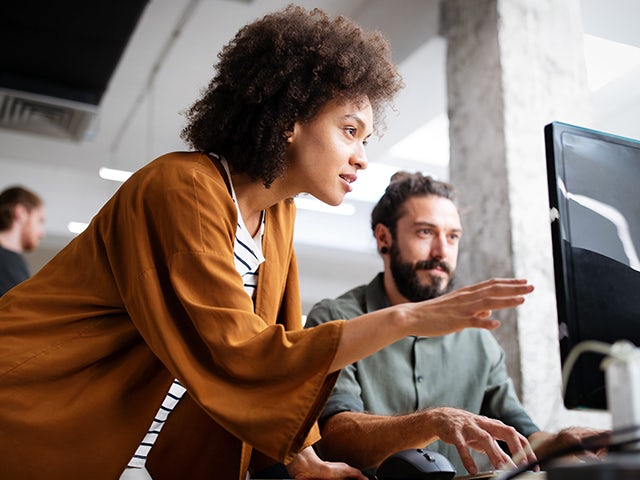 A student and her mentor examining a computer screen.
