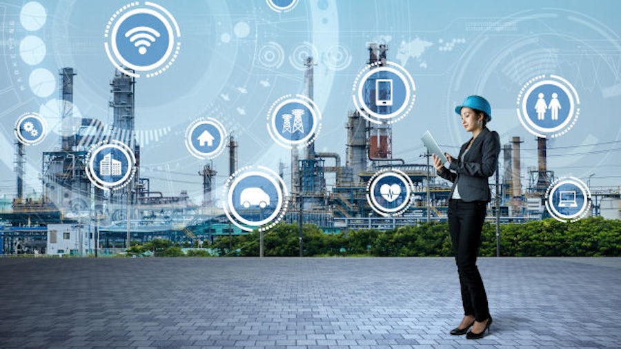 Digital icons around a female engineer in front of a rafinery