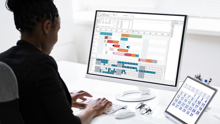 Woman sitting in front of a computer using production planning and scheduling software