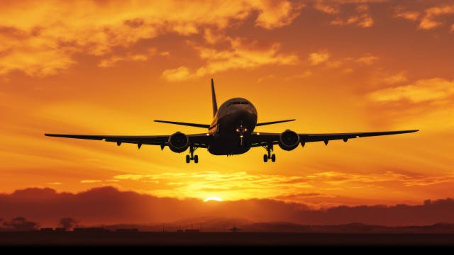 A commerical aircraft not far off the ground with the setting sun back-lighting the aircraft