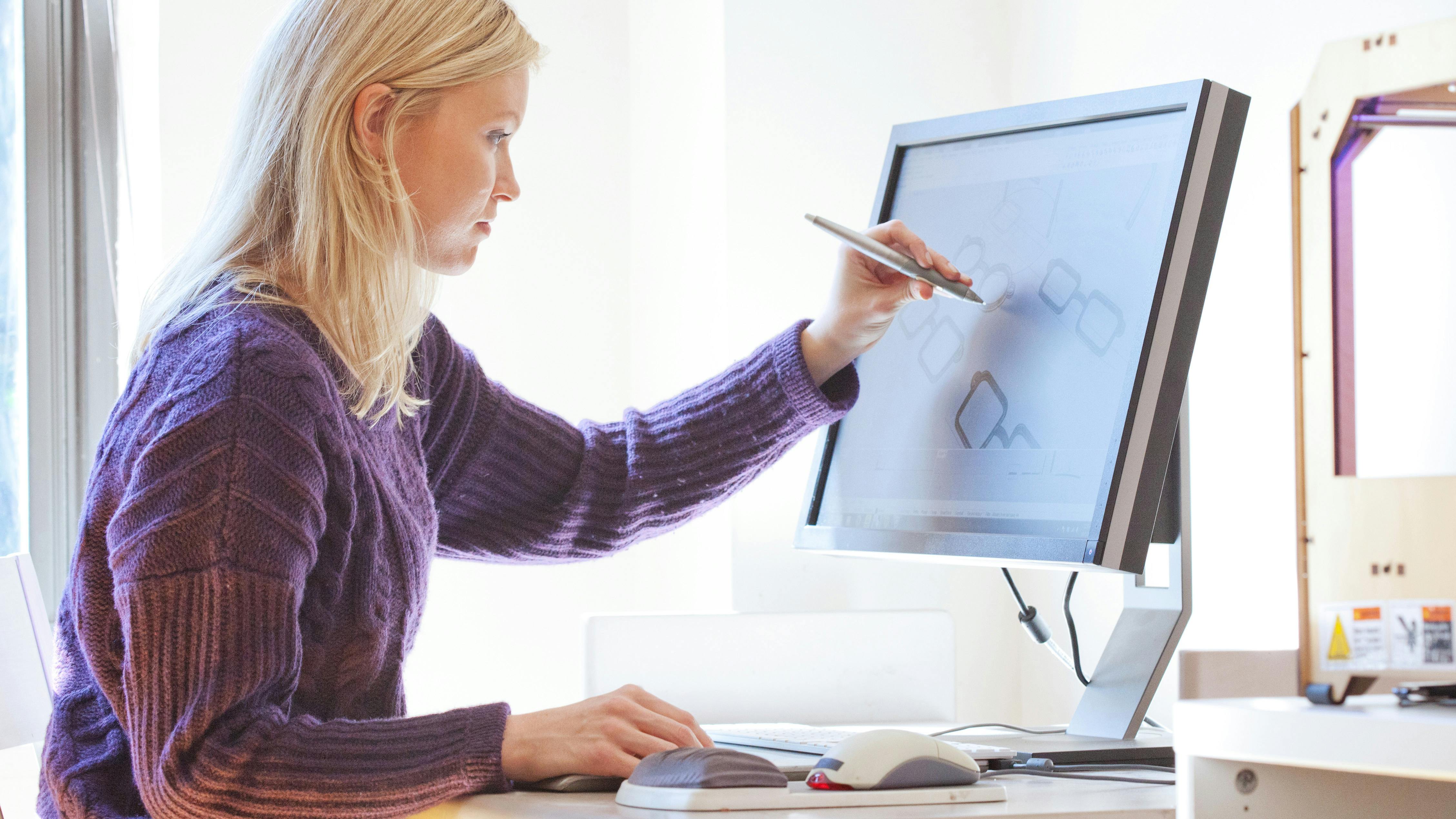 Woman using a touch screen monitor to design a product 