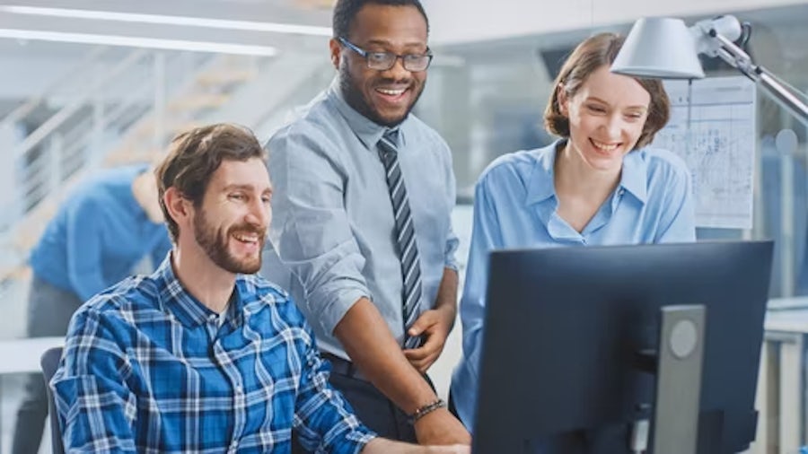 Tre ingegneri collaborano a una postazione di lavoro con un software PLM.