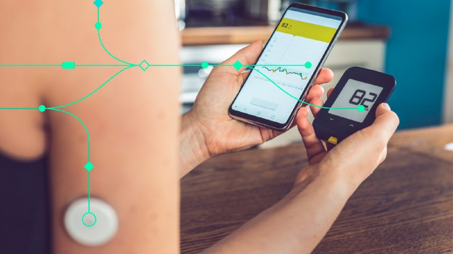 Woman checking glucose levels on smart phone from a small, wireless device attached on her arm.